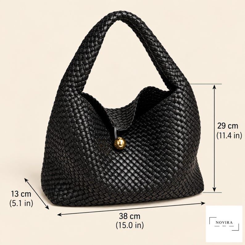 May include: A black woven handbag featuring a single handle and a gold-toned spherical clasp. The bag measures 38 cm in width, 29 cm in height, and 13 cm in depth. The text Novira Bag is visible in the bottom right corner of the image.