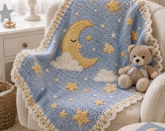 May include: A light blue crochet blanket featuring a yellow crescent moon with a sleeping face, white clouds, and yellow stars. The blanket has a white scalloped border and is draped over a chair next to a small brown teddy bear with a blue ribbon.