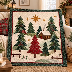 May include: A quilted throw blanket featuring a winter landscape with evergreen trees, a cabin with a smoking chimney, and a large gold star. The design includes red, green, and cream fabric patches with a dark green border and red trim.