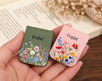 Può includere: Due segnalibri magnetici rettangolari in materiale simile alla pelle. Uno è verde oliva con il nome Rachel e una stampa di fiori di campo. L'altro è rosa chiaro con il nome Crystal e un motivo floreale simile.