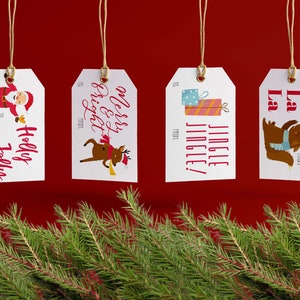 Puede incluir: Cuatro etiquetas de regalo blancas con ilustraciones y texto rojos y negros. Las etiquetas están colgadas de un cordel sobre un fondo rojo. El texto en las etiquetas dice "Holly Jolly", "Merry & Bright", "Jingle Jingle!" y "Fa La La".