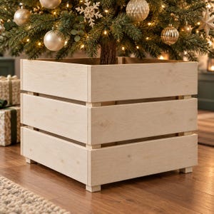 Puede incluir: Un cubrepié de árbol cuadrado de madera clara, construido con tres tablones horizontales en cada lado. La base en forma de caja presenta un acabado liso de veta de madera natural y se asienta directamente sobre el suelo rodeando el tronco.