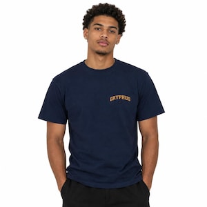 Pode incluir: Uma t-shirt azul-marinho de manga curta com gola redonda e a palavra GRYPHUS impressa numa fonte dourada arqueada de estilo universitário na parte superior esquerda do peito. A peça é feita de tecido de cor sólida com design simples.
