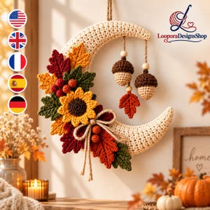 Könnte beinhalten: Ein halbmondförmiger Wandbehang aus cremefarbenem Garn, verziert mit gehäkelten Herbstblättern in Rot, Orange und Grün, einer gelben Sonnenblume, roten Beeren und zwei hängenden gehäkelten Eicheln mit Holzperlen an einer Juteschnur.
