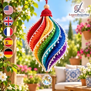 May include: A spiral-shaped crochet ornament featuring vibrant rainbow-colored segments in red, orange, yellow, green, blue, and purple. The edges are trimmed with small white beads, and a clear faceted crystal prism hangs from the bottom point.