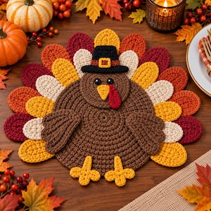 May include: A round, crocheted turkey placemat featuring a brown body, yellow feet, and a fan of layered feathers in shades of red, orange, yellow, and cream. The turkey wears a black pilgrim hat with a yellow buckle and has a red wattle.