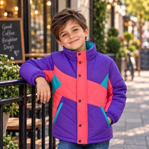 Könnte beinhalten: Eine Steppjacke mit einem Color-Block-Design in Lila, leuchtendem Pink und Türkis. Die Jacke hat einen hohen Kragen, eine Knopfleiste mit schwarzen Druckknöpfen, lange Ärmel mit elastischen Bündchen und zwei Seitentaschen mit türkisen Akzenten.