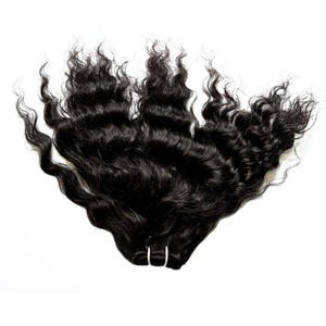 Puede incluir: Un paquete de extensiones de cabello largo de color negro oscuro con una textura ondulada natural. El cabello está recogido y sujeto en la base con una banda fina de color claro, abriéndose en ondas sueltas y voluminosas con brillo.