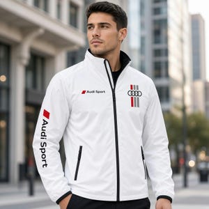 Pode incluir: Um casaco branco com fecho de correr, apresentando o logótipo Audi Sport no peito e na manga. O design inclui um forro de gola preto, fecho de correr preto e um gráfico vertical com o emblema de quatro anéis e riscas vermelhas, cinzentas e pretas.