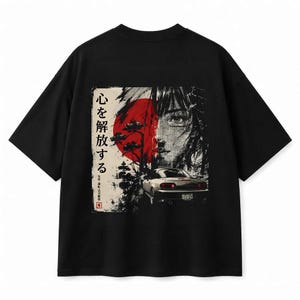 Może przedstawiać: Czarny t-shirt z krótkim rękawem z nadrukiem graficznym na plecach. Wzór zawiera czerwoną słońce, stylizowany portret, biały samochód sportowy oraz japoński tekst 心を解放する. Grafika wykorzystuje kontrastowe cieniowanie w kolorze czarnym i białym.