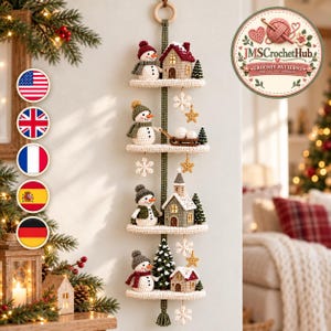 Può includere: Una decorazione da parete verticale con quattro ripiani all'uncinetto sovrapposti, decorati con pupazzi di neve, casette, una chiesa, alberi sempreverdi e ornamenti pendenti a forma di fiocco di neve e stella, fissata a un nastro verde.