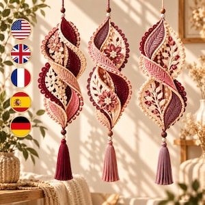 May include: Three hanging spiral ornaments featuring intricate crochet and lace work in shades of burgundy, pink, and cream. Each piece is adorned with floral motifs, small white beads, and a long, matching colored tassel at the bottom.