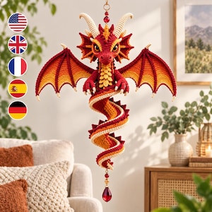 Puede incluir: Un adorno de dragón de ganchillo colgante con un esquema de colores rojo y naranja vibrante, con cuernos y garras de color crema. El dragón tiene alas grandes, una cola larga en espiral y un colgante de cristal rojo facetado en la parte inferior.