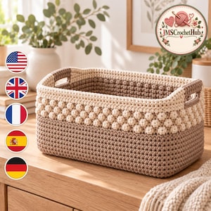 Pode incluir: Um cesto de armazenamento retangular em crochê com um design bicolor, apresentando uma base em bege escuro sólido e uma secção superior em creme texturizado com um padrão de pontos de bolha e pegas laterais integradas para transporte.