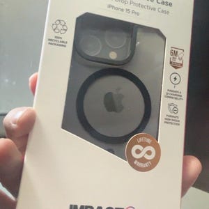 May include: A white rectangular retail box for an iPhone 15 Pro premium protective case. The packaging features the text Premium Protective Case, High Impact Drop Protective Case, and Impact Zero. It includes icons for 6M drop protection, MagSafe compatibility, and a lifetime warranty sticker.