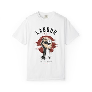 May include: A white short-sleeve t-shirt featuring a graphic of a raised fist centred over a distressed red circle. The text "LABOUR DAY" is arched above the fist, and the words "WORK. BUILD. PROGRESS." are printed below with a small red star.