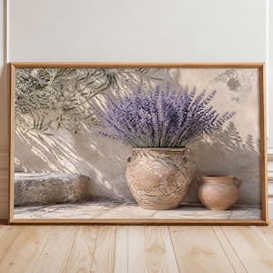 May include: A framed wall art print depicting a large, textured, light brown ceramic urn filled with a dense bouquet of purple lavender flowers, positioned next to a smaller matching ceramic pot and a stone block against a sunlit wall.