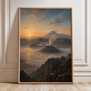 Könnte beinhalten: Ein gerahmter Landschaftsdruck, der eine vulkanische Bergkette bei Sonnenaufgang zeigt. Die Szene zeigt einen rauchenden Vulkan, der sich über einem Nebelmeer erhebt, mit einem größeren Berg in der Ferne unter einem goldenen Himmel. Heller Holzrahmen.