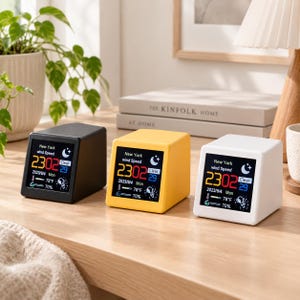 Può includere: Tre orologi meteo digitali in nero, giallo e bianco. Ogni dispositivo presenta uno schermo che mostra la velocità del vento a New York, l'ora 23:02, la data 2023/9/4, la temperatura 78°F e il 70% di umidità con un'icona di cielo sereno e luna.