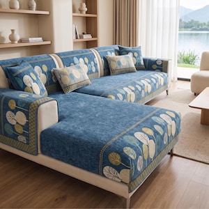 May include: A sectional sofa covered in blue fabric featuring a repeating pattern of stylized trees in shades of green, yellow, and white. The sofa includes matching rectangular throw pillows and rectangular seat covers with a dark green border.