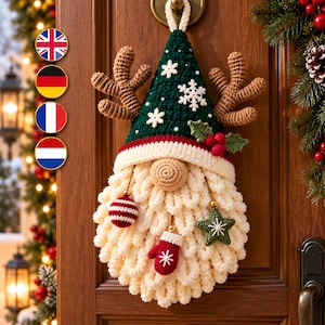 May include: A crocheted gnome wall hanging featuring a dark green pointed hat with white snowflake appliques, brown antlers, a cream-colored beard, and hanging ornaments including a red and white striped ball, a red mitten, and a green star.