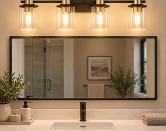 May include: A four-light vanity wall fixture featuring a matte black horizontal bar and rectangular wall plate. Each light has a cylindrical clear glass shade with a brass-toned socket and a warm-toned Edison-style light bulb inside.