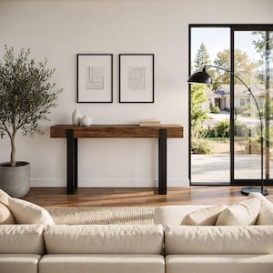 May include: A rectangular console table featuring a thick, dark brown wooden top with a natural grain texture, supported by two sturdy, matte black metal legs. The table is positioned against a white wall, holding two small white ceramic vases.
