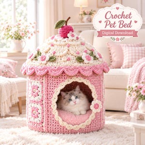 May include: A pink and cream crochet pet bed shaped like a cupcake with a cherry on top, featuring floral accents and a scalloped roof. A fluffy cat sits inside the arched opening. The text Crochet Pet Bed Digital Download is visible.