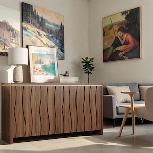 May include: A rectangular wooden sideboard featuring vertical wavy carved patterns on the cabinet doors and a thin gold-toned metal trim along the top edge. The piece stands on a flat base and has a smooth, dark brown wood grain finish.