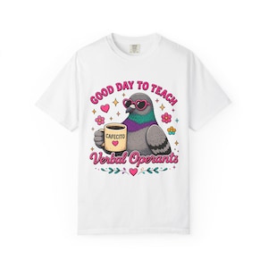 Op de afbeelding: Een wit t-shirt met korte mouwen en een afbeelding van een grijze duif met een roze hartvormige zonnebril die een beige mok vasthoudt met de tekst Cafecito en een hartje. De tekst luidt Good Day To Teach Verbal Operants in roze letters.