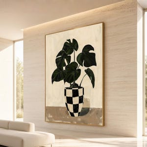 Puede incluir: Una impresión de arte mural enmarcada que muestra una planta monstera de color verde oscuro con hojas grandes y divididas en una maceta a cuadros blancos y negros. La planta descansa sobre una superficie plana marrón claro y fondo crema.