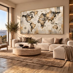 May include: A large rectangular wall art piece featuring a world map with abstract brushstrokes in shades of black, gold, and cream. The map includes labeled continents and oceans with a compass rose in the lower left corner, framed in a thin gold border.