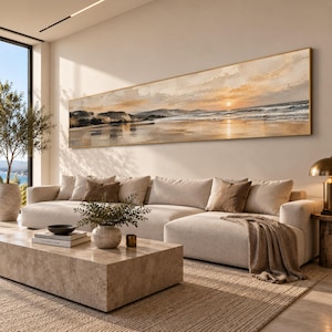 Op de afbeelding: Een lang, horizontaal rechthoekig wandkunstwerk met een olieverfschilderij van een kustlandschap bij zonsondergang. De scène toont een kalme oceaan met zachte golven, een zandstrand en verre kliffen onder een zachte, goudkleurige lucht.