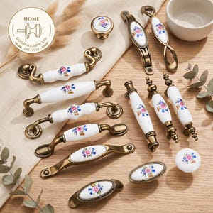 May include: A collection of cabinet hardware including various drawer pulls and knobs featuring white ceramic centres with floral patterns and antique brass-toned metal accents. The set includes curved handles, oval pulls, and round knobs with floral designs.