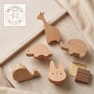 Peut inclure: Un ensemble de cinq boutons de placard en bois clair en forme de girafe, tortue, éléphant, baleine et lapin, avec une petite plaque carrée en laiton et un bloc carré en bois foncé, et un logo BRASSELLE HOME DOOR HARDWARE.