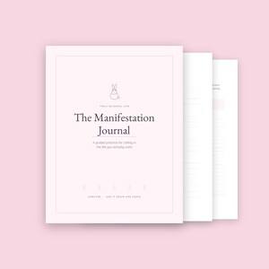 Puede incluir: Un diario de color rosa claro titulado The Manifestation Journal con un pequeño icono de conejo, el texto Truly Blissful Life y el subtítulo A guided practice for calling in the life you actually want, con páginas adicionales que muestran secciones rayadas.