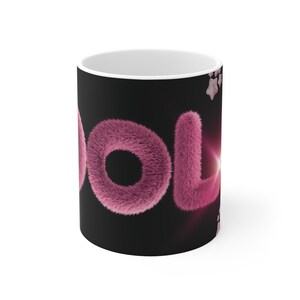 Könnte beinhalten: Ein Keramikbecher mit schwarzem Hintergrund, der das Wort "LOL" in großen, rosa, flauschigen, fellartigen Buchstaben zeigt. Das Design enthält kleine, hellrosa Sternformen oben und unten rechts sowie einen dezenten Lichteffekt am Buchstaben L.