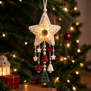 May include: A cream-colored crocheted star ornament featuring a central wooden button with a snowflake design and internal warm lighting. It hangs with beaded strings adorned with small crocheted stars, bells, and a green tree at the bottom.