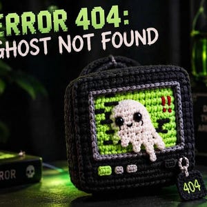 May include: A black crocheted television set featuring a bright green screen with a white ghost character. The screen displays the text ERROR 404: GHOST NOT FOUND. A small black square tag attached to the television by a ring displays the number 404.