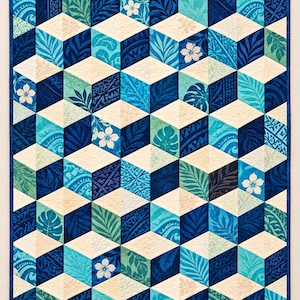 Puede incluir: Una colcha rectangular con un patrón geométrico de cubos tridimensionales en tonos azul marino, turquesa y crema. Los paneles de tela están decorados con estampados de hojas tropicales y motivos de flores de hibisco blancas.