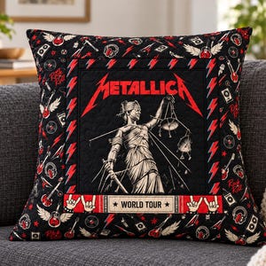 May include: A square quilted throw pillow featuring a central graphic of the Lady Justice statue with the Metallica logo in red text above. The border displays a pattern of red lightning bolts, guitars, and headphones on a black background.