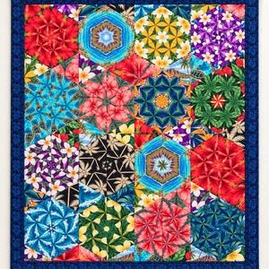 May include: A rectangular quilt featuring a repeating pattern of hexagonal blocks. Each hexagon displays a kaleidoscope-style print of tropical flowers, palm trees, ocean waves, and sea turtles in vibrant red, blue, yellow, and green hues.