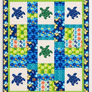 May include: A rectangular quilt featuring a patchwork design of blue, green, and white floral fabrics. The quilt includes five appliquéd sea turtle shapes in blue and green, set against cream-colored squares with a swirling quilted texture.