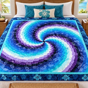 May include: A quilt featuring a vibrant spiral pattern in shades of blue, purple, and white. The center radiates outward with small fabric squares, surrounded by a border of dark blue fabric decorated with a repeating light blue hibiscus flower print.