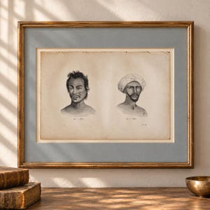 以下が含まれることがあります： 男性の頭部を描いた2つの白黒インクイラストが特徴のヴィンテージ風額入りプリント。左の図には「Fig. 1 - Malay」、右の図には「Fig. 2 - Hindo」と記されています。プリントはグレーのマット台紙とゴールド調の木製フレームに収められています。