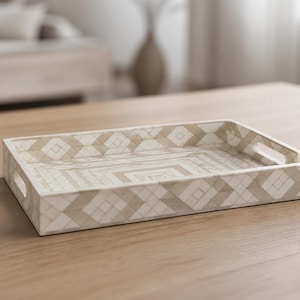 May include: A rectangular serving tray featuring a geometric pattern in shades of cream and beige. The tray has low sides with integrated cutout handles on the short ends and a flat base with a repeating diamond and square inlay design.