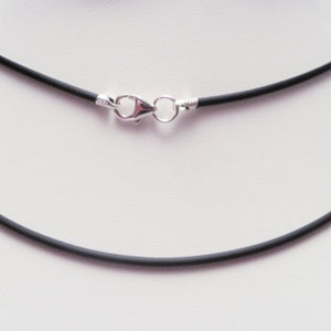 May include: A black rubber necklace with a silver clasp. The necklace is 2mm thick.