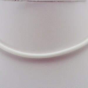 May include: A white, simple, and minimalist choker necklace made of a smooth, round cord.