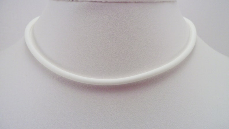 May include: A white, simple, and minimalist choker necklace made of a smooth, round cord.