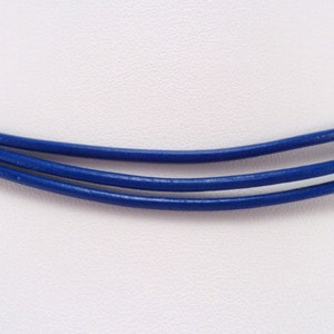 May include: A triple-strand blue leather cord necklace. The cord is smooth and has a slight sheen.